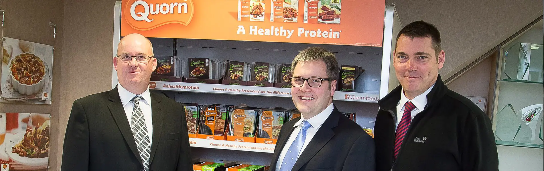 A group of Quorn employees standing in front of a display shelf of products.