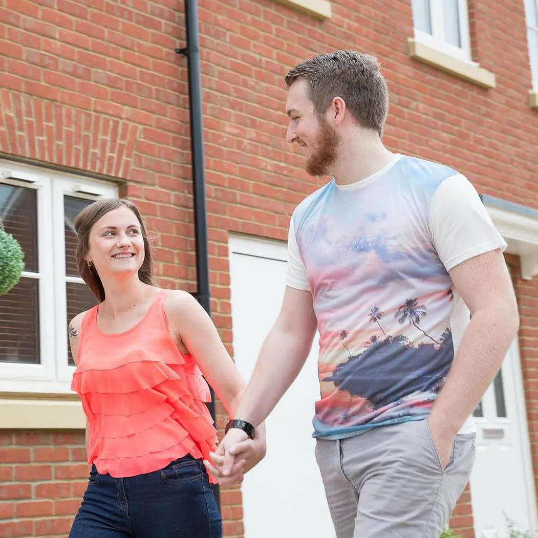 A couple walking in front of a house, smiling.