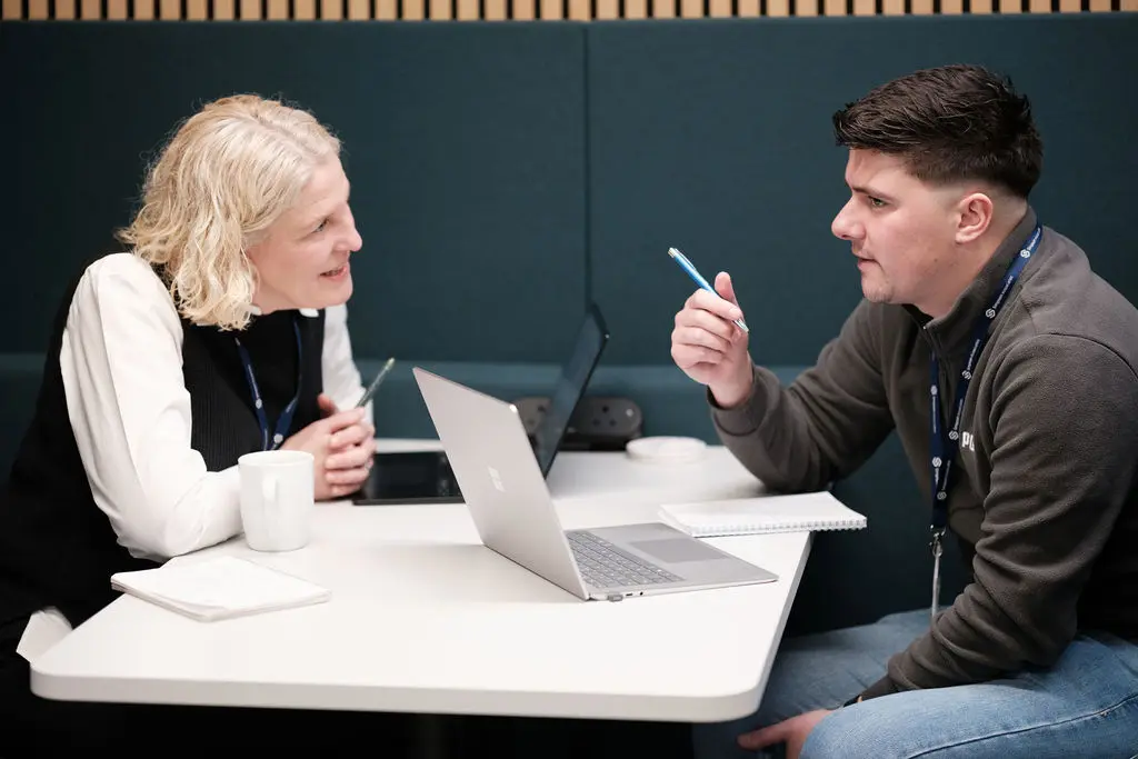 two team members talking over a table with a laptop