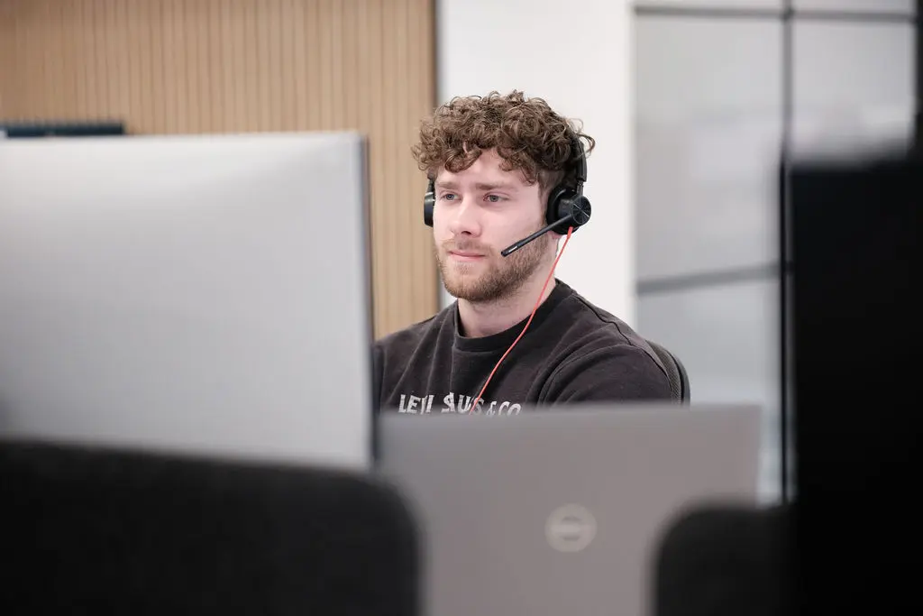 office worker sat at desk wearing a headset.