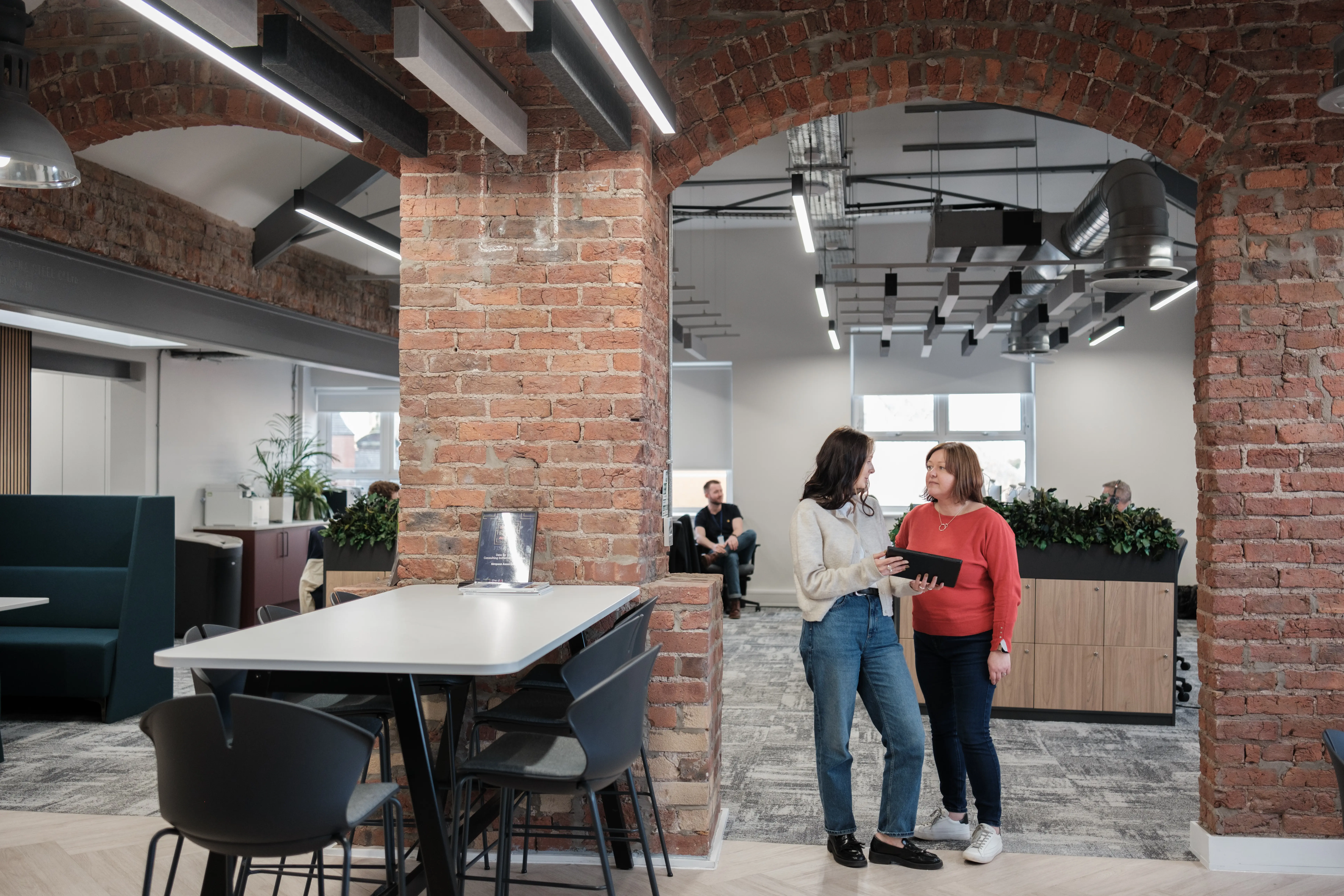 two people stood in office talking over a tablet.