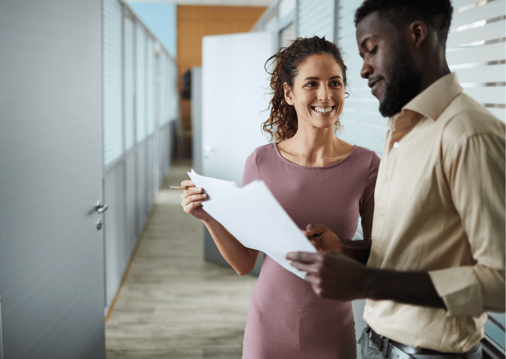 two people stood in a hallway, discussing paperwork